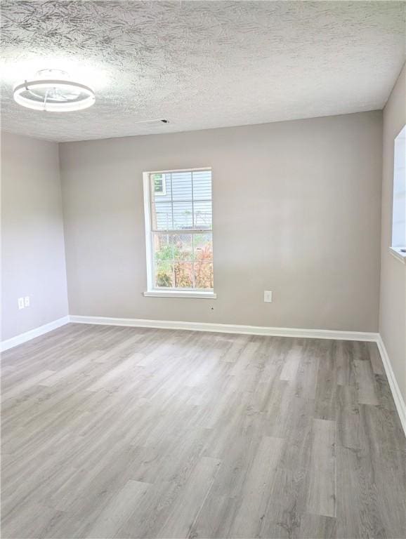 spare room featuring baseboards, a textured ceiling, and wood finished floors