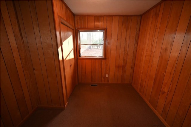 unfurnished room with carpet floors and wood walls