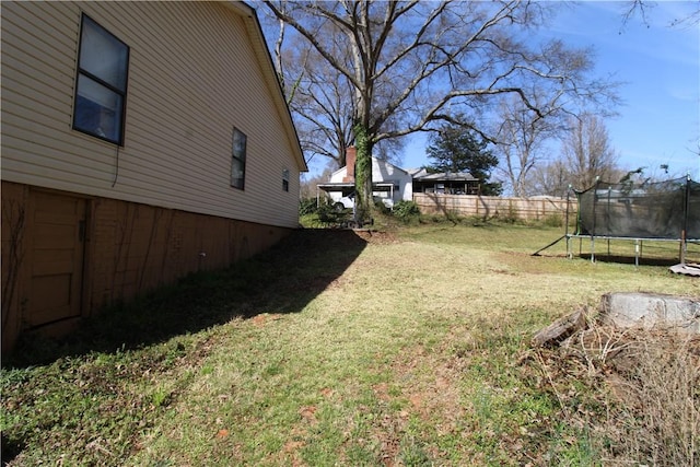 view of yard with a trampoline and fence