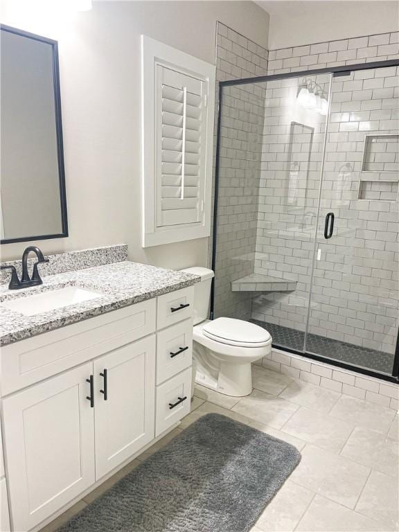 bathroom with tile patterned floors, vanity, an enclosed shower, and toilet