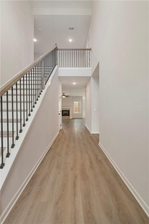 stairway featuring a towering ceiling, wood-type flooring, and ceiling fan