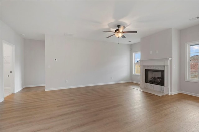 unfurnished living room with a premium fireplace, ceiling fan, and light hardwood / wood-style floors