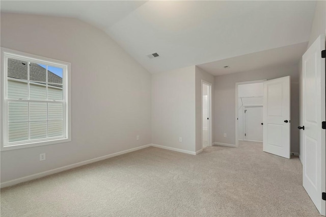 unfurnished room with lofted ceiling and light carpet