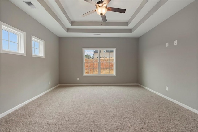 carpeted spare room featuring ceiling fan and a tray ceiling