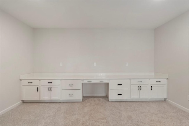 unfurnished office featuring light colored carpet and built in desk