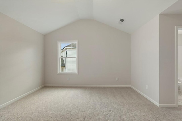 empty room with vaulted ceiling and light colored carpet