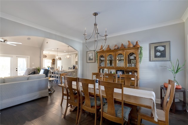 dining space featuring ceiling fan with notable chandelier, crown molding, and dark wood-type flooring