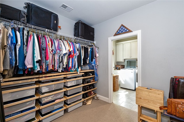 spacious closet featuring light tile patterned floors and washing machine and clothes dryer