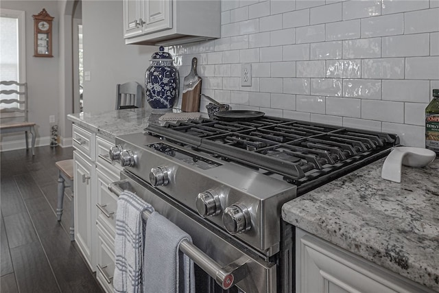 details featuring dark wood-type flooring, white cabinets, high end stainless steel range oven, decorative backsplash, and light stone countertops