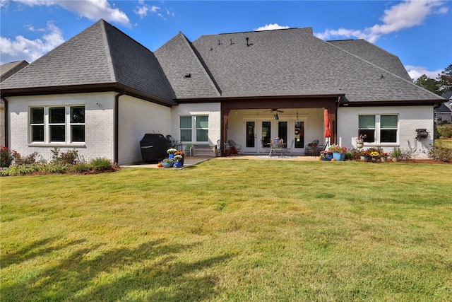 rear view of property featuring a lawn, ceiling fan, a patio, and french doors