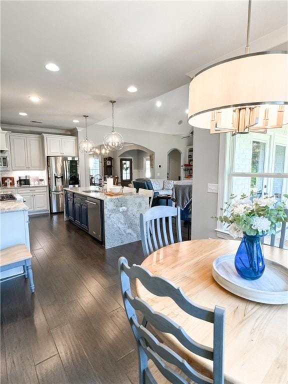 dining room featuring sink, dark wood-type flooring, and an inviting chandelier