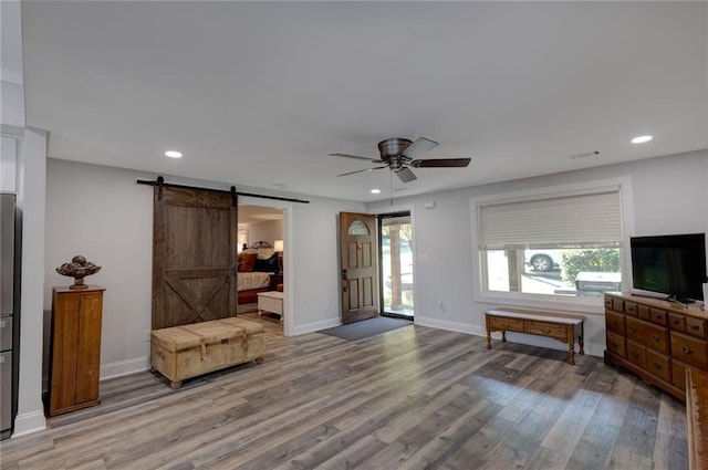 entrance foyer with hardwood / wood-style floors, ceiling fan, and a barn door