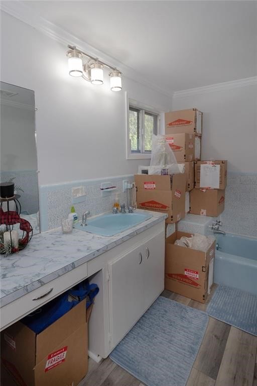 bathroom with a tub, hardwood / wood-style flooring, vanity, and ornamental molding