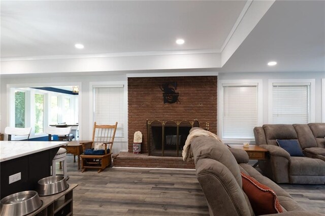 living room with a brick fireplace, dark hardwood / wood-style flooring, and ornamental molding