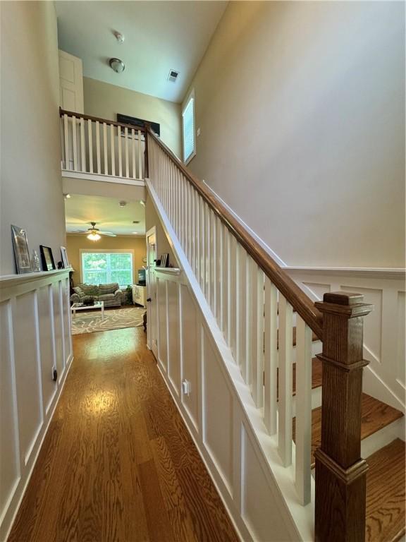 1521 Reynolds Dr, Auburn, AL 36830 - stairway featuring wood finished floors, a ceiling fan, a decorative wall, and a towering ceiling