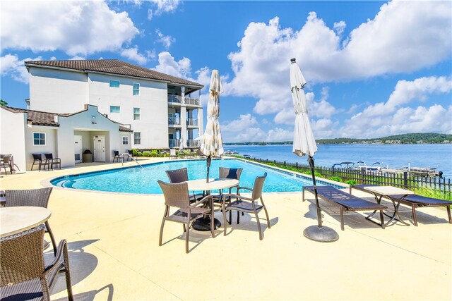 view of pool featuring a water view and a patio