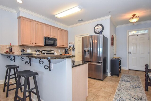 kitchen with kitchen peninsula, crown molding, light tile patterned floors, and appliances with stainless steel finishes