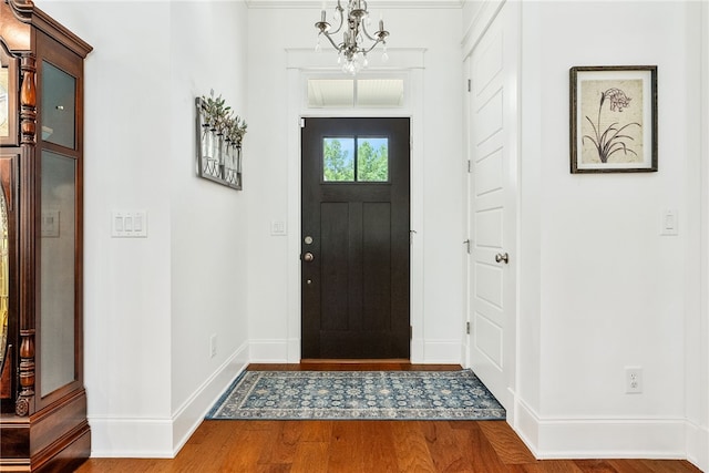 entrance foyer featuring a notable chandelier, wood finished floors, and baseboards