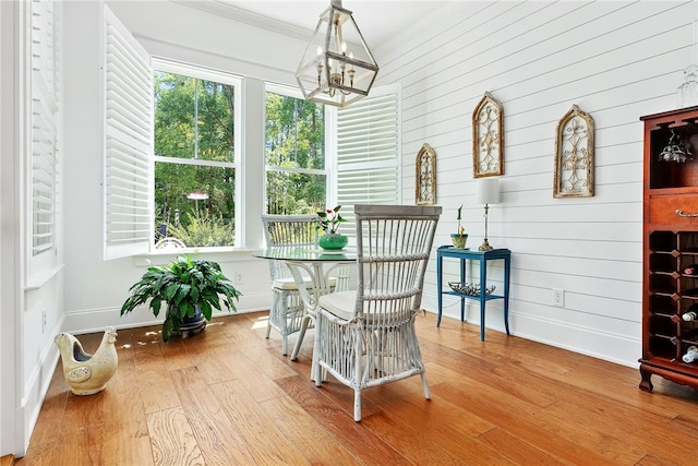 dining room featuring a notable chandelier, ornamental molding, baseboards, and wood finished floors