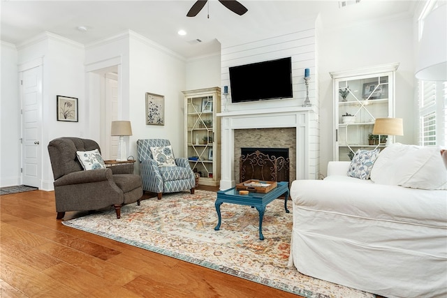 living area with a fireplace, wood finished floors, visible vents, and ornamental molding