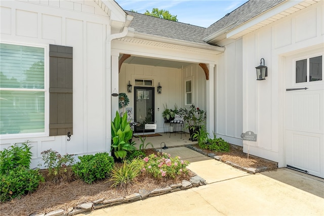 view of exterior entry featuring a porch, an attached garage, board and batten siding, and roof with shingles