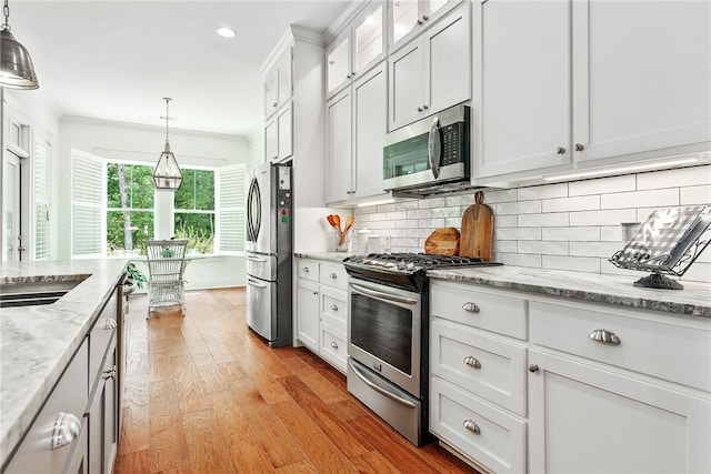 kitchen featuring backsplash, appliances with stainless steel finishes, white cabinetry, and light wood-style floors