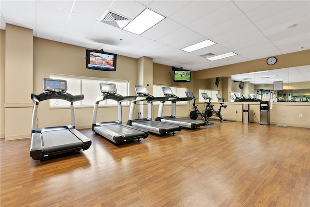 workout area with visible vents, a paneled ceiling, baseboards, and wood finished floors