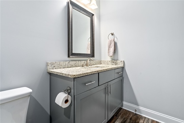 bathroom with baseboards, toilet, wood finished floors, and vanity