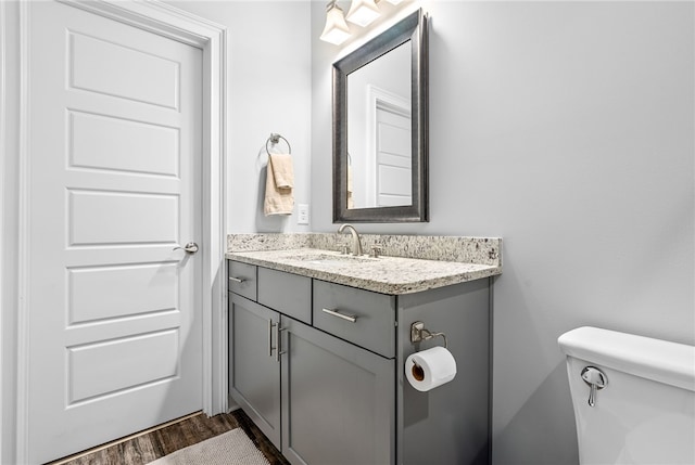 half bathroom with vanity, toilet, and wood finished floors