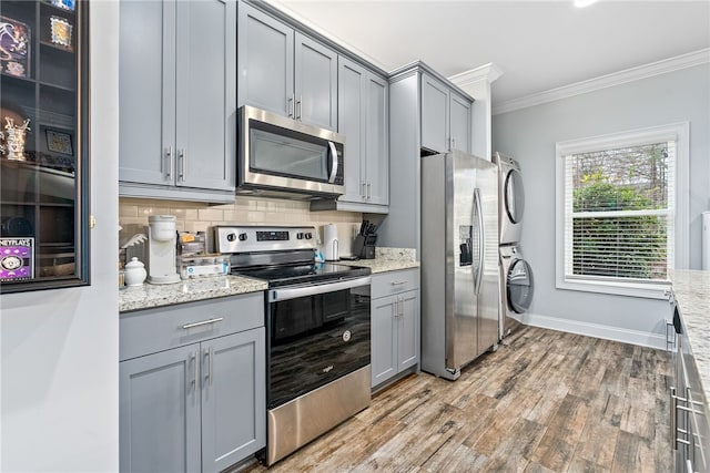 kitchen featuring gray cabinets, stainless steel appliances, and stacked washing maching and dryer