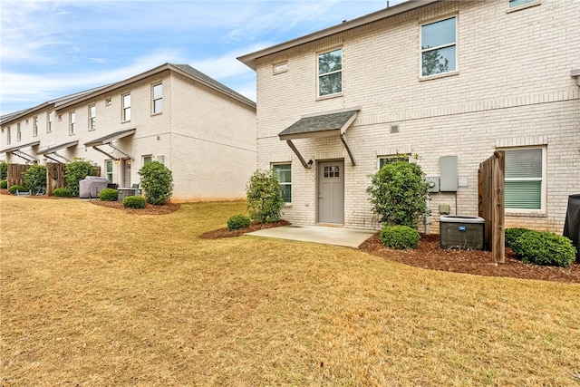 rear view of property with a yard, central AC unit, and brick siding