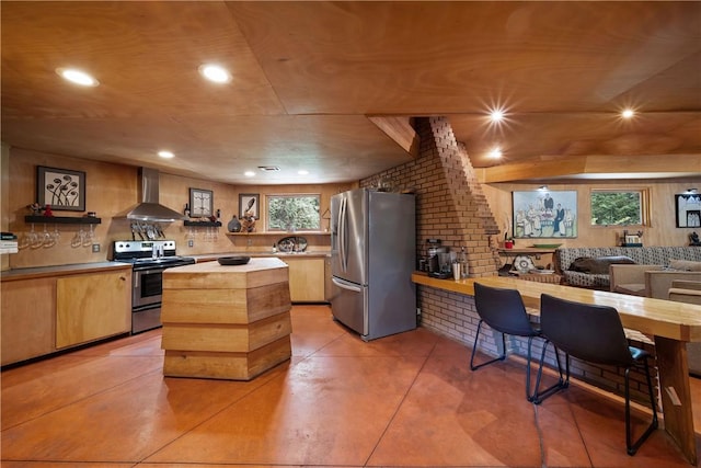 kitchen featuring a center island, open floor plan, recessed lighting, wall chimney range hood, and appliances with stainless steel finishes