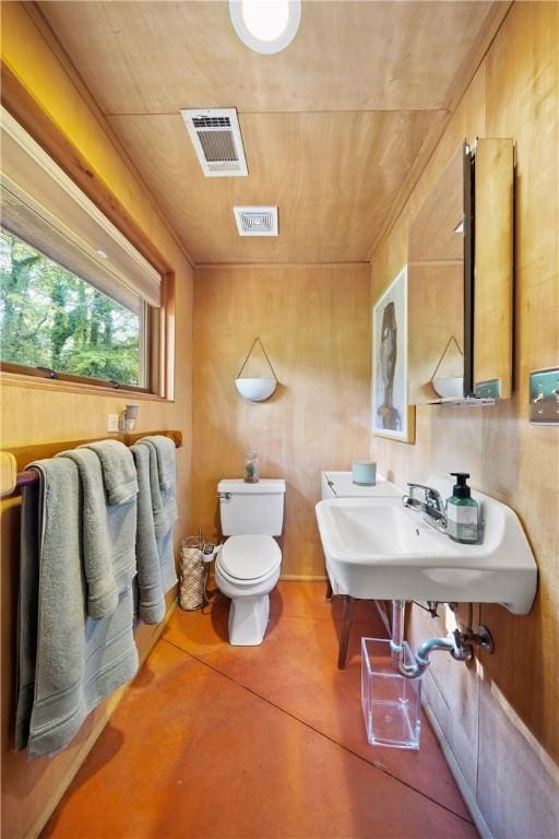 half bath with concrete flooring, visible vents, toilet, and a sink