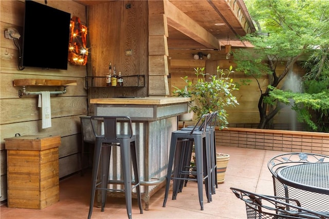 bar with tile patterned flooring, a bar, and wooden walls