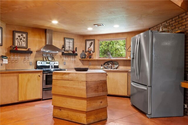 kitchen featuring wall chimney range hood, stainless steel appliances, light countertops, and a kitchen island