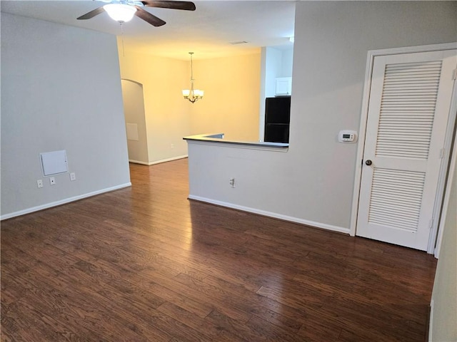 spare room with dark wood-type flooring and ceiling fan with notable chandelier