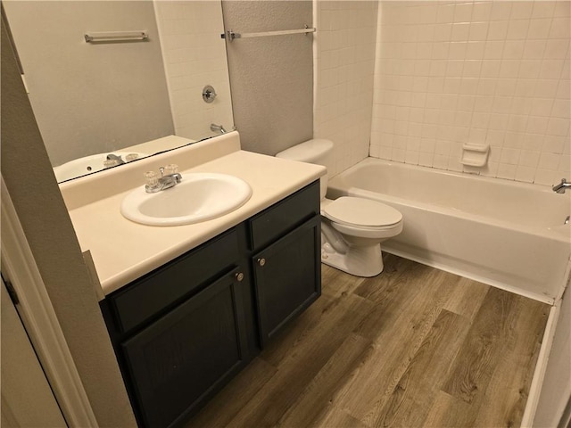 full bathroom featuring hardwood / wood-style floors, vanity, toilet, and tiled shower / bath combo