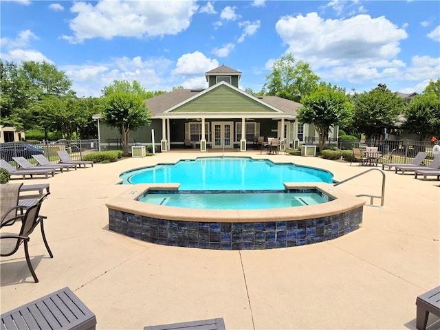 view of swimming pool featuring a community hot tub, a patio, and french doors