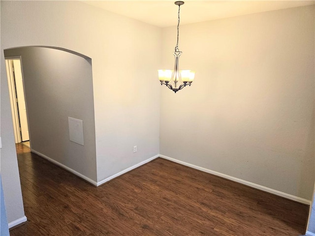 empty room featuring dark hardwood / wood-style flooring and a chandelier