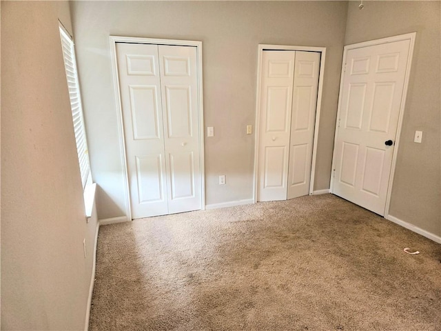 unfurnished bedroom featuring carpet and two closets