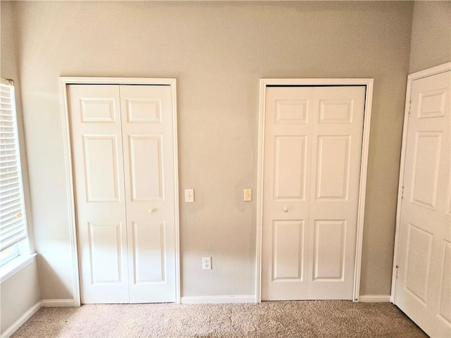 unfurnished bedroom with multiple closets and carpet