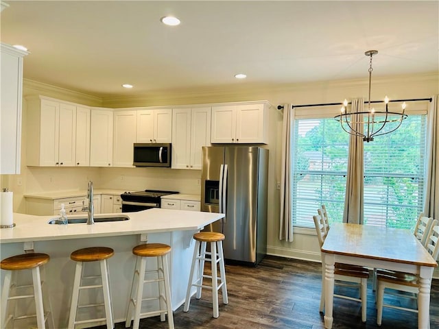 kitchen with a sink, ornamental molding, dark wood-style flooring, a notable chandelier, and appliances with stainless steel finishes