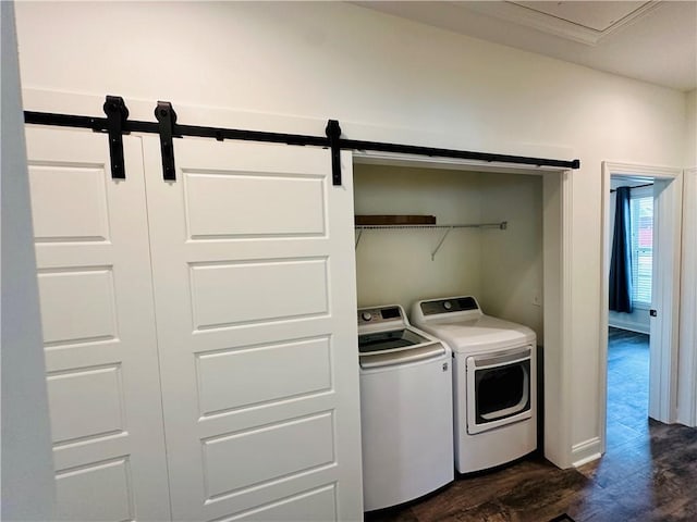laundry area featuring a barn door, baseboards, washer and dryer, laundry area, and dark wood-style floors