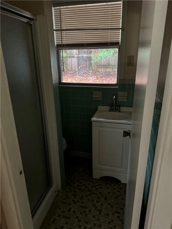 bathroom featuring vanity, toilet, tile walls, and walk in shower