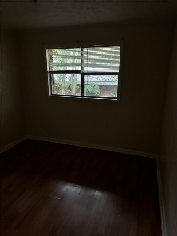 unfurnished room with dark hardwood / wood-style flooring and a wealth of natural light