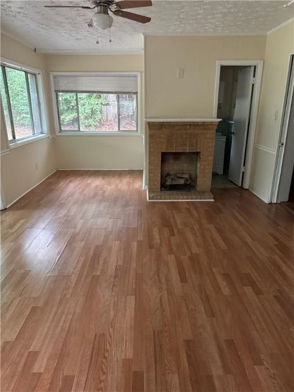 unfurnished living room featuring a textured ceiling, ceiling fan, wood-type flooring, and a fireplace