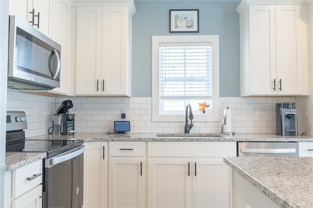 kitchen featuring decorative backsplash, appliances with stainless steel finishes, white cabinetry, and sink