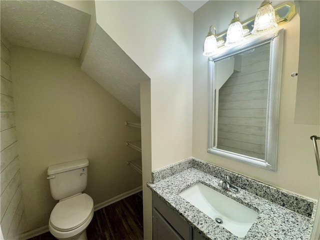 bathroom featuring vanity, toilet, baseboards, a textured ceiling, and wood finished floors