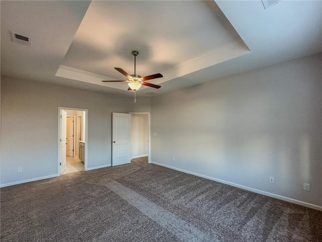 unfurnished bedroom with ceiling fan, light colored carpet, a tray ceiling, and ensuite bath