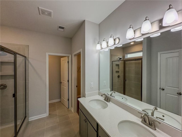 bathroom with tile patterned floors, a shower with door, and vanity